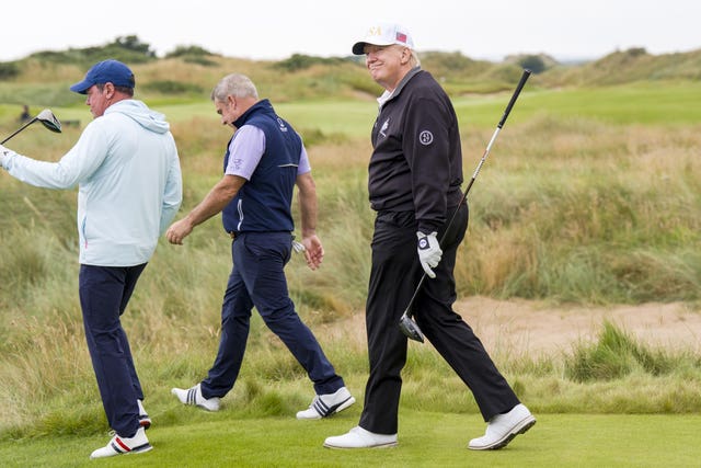 Donald Trump walking on a golf course, holding a club