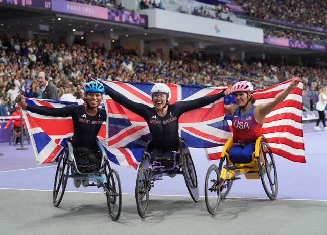 Great Britain's Hannah Cockroft (centre) celebrates winning gold, alongside Great Britain's Kare Adenegan (left) and USA's Eva Houston after the Women's 800m T34 final at the 2024 Paralympics