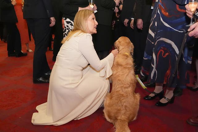 The Duchess of Edinburgh crouches down with Liberal Democrat MP Steve Darling’s golden retriever guide dog Jennie at Buckingham Palace as she looks up to talk to guests 