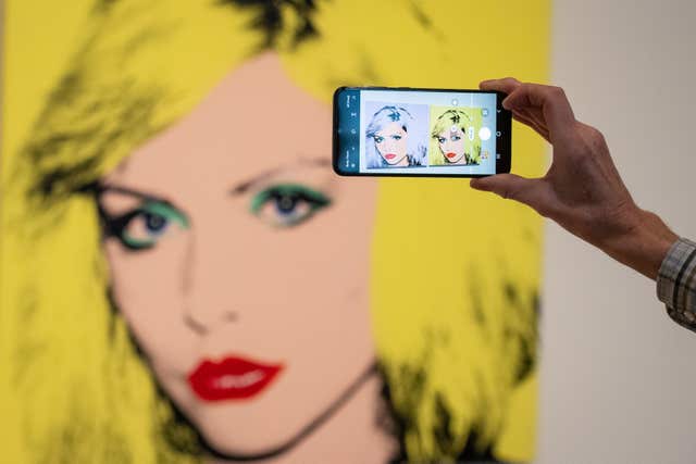 A man takes a photo of Debbie Harry, at a press view of a major new Andy Warhol exhibition at Tate Modern 