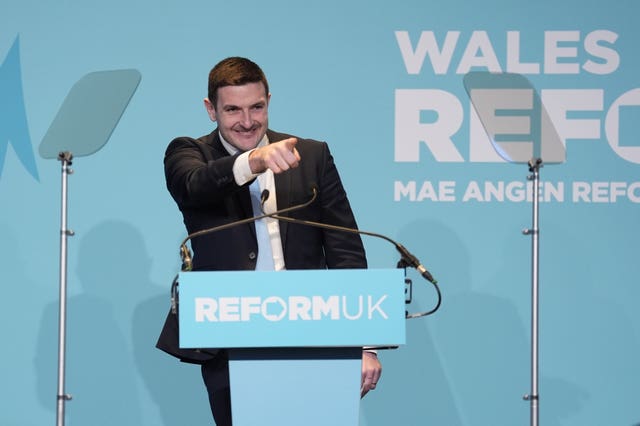 James Evans pointing into the audience while standing behind a Reform UK lectern