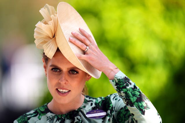 Princess Beatrice hangs on to her hat following a gust of wind