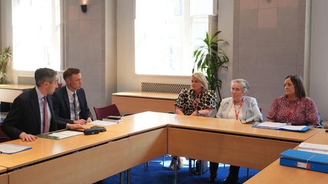 Tanaiste Simon Harris (left) speaking to Sean Brown's widow Bridie Brown (second right) and daughters Clare Loughlan (centre) and Siobhan Brown (right) 