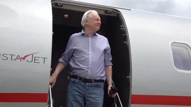 Julian Assange steps out of an aircraft door