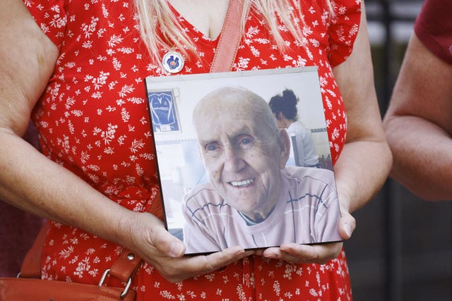 People hold pictures of loved ones lost during the pandemic, outside the UK Covid-19 Inquiry