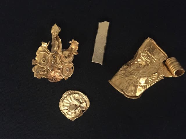 A gold bracteate, which is a type of stamped pendant, a small gold bar, and two other pieces of gold which were probably parts of larger items of jewellery
