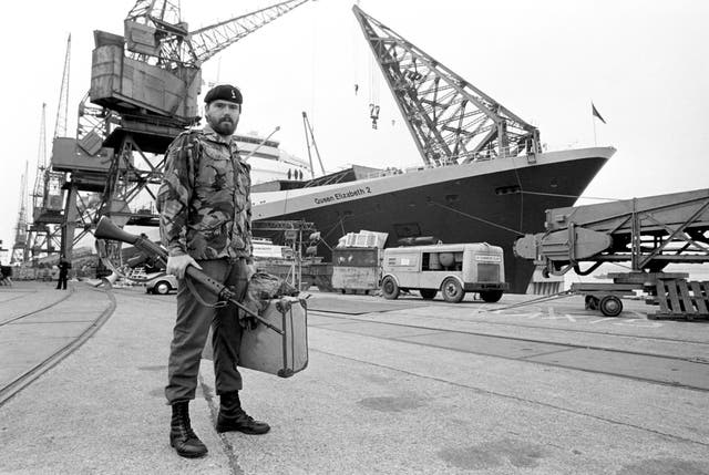 A soldier stands in front of the QE2 on the quayside at Southampton before the Falklands War (PA) 