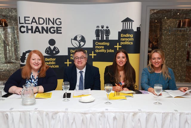 (left to right) Alliance leader Naomi Long and parliamentary candidates for North Down Stephen Farry, Lagan Valley Sorcha Eastwood and South Belfast Kate Nicholl seated at a long white table in front of a banner showing points from the party's Leading Change manifesto 