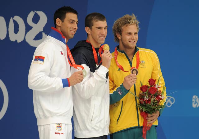Michael Phelps, centre, with his men’s 100m butterfly final gold 