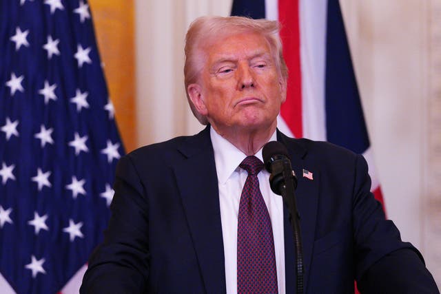 Donald Trump standing behind a microphone in front of UK and US flags