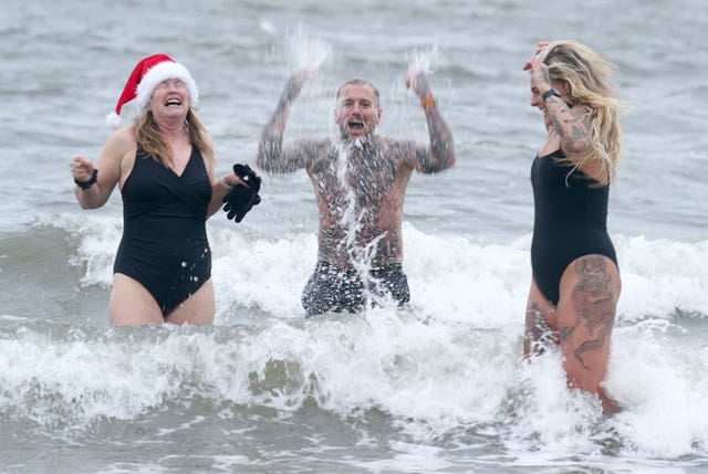 Three swimmers splashing in the water at Cullercoats Bay in North Tyneside 
