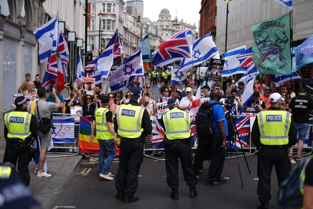 Police watch protesters holding British and Israeli flags in a central London street