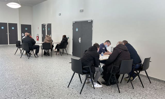 Ukrainian refugees who have fled the conflict sit with British government officials filling out paperwork as they seek to enter the UK, at the ferry terminal in Calais, France 