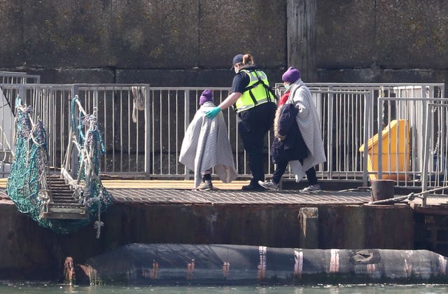 A Border Force officer helps a small child as a group of people thought to be migrants are brought into Dover, Kent in April