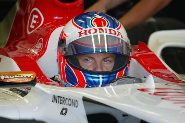 A helmeted Jenson Button sits in his Formula One car