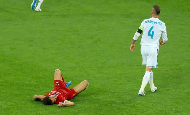Liverpool forward Mohamed Salah lies on the floor injured as Real Madrid defender Sergio Ramos walks away
