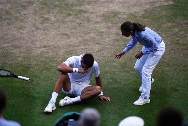 The umpire checks on Novak Djokovic after his slip