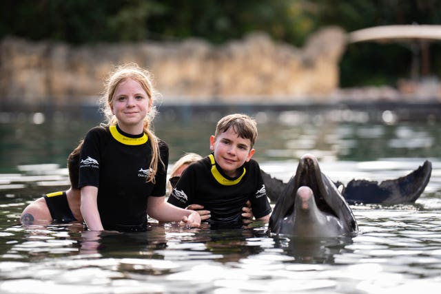 Siblings Lottie Scott, 14, and Tommy Scott, 11, with a dolphin during the Dreamflight visit to Discovery Cove in Orlando