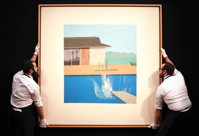 Auction employees hold The Splash by David Hockney  
