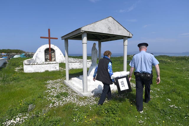 Garda Alan Gallagher and Presiding Officer Carmel McBride carry a polling box used by the few people that live off the coast of Donegal on the island of Inishbofin (Clodagh Kilcoyne/PA)