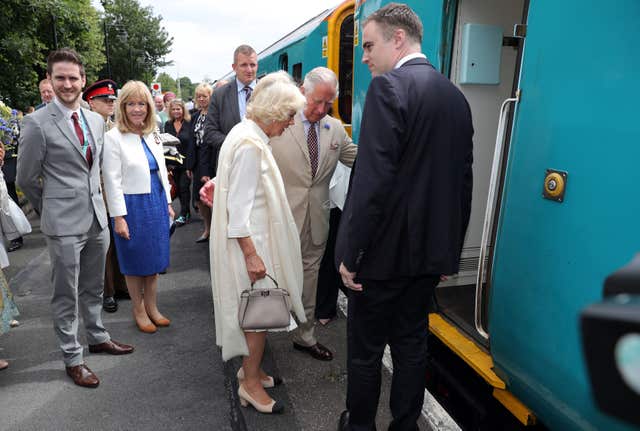 The Prince of Wales helps the Duchess of Cornwall board a train during a visit to Llandovery Railway Station to mark the 150th anniversary of the Heart of Wales railway line. Andrew Matthews/PA Wire
