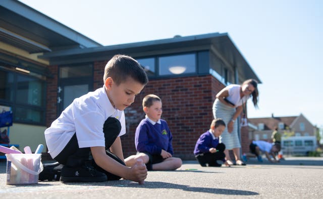 Reception pupil Ollie draws with chalk in the playground at Queen’s Hill Primary School in Costessey, Norfolk