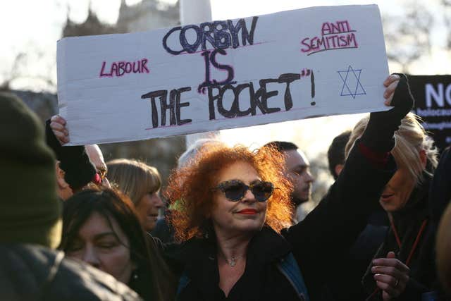 A woman holds aloft a placard during the protest (Yui Mok/PA)