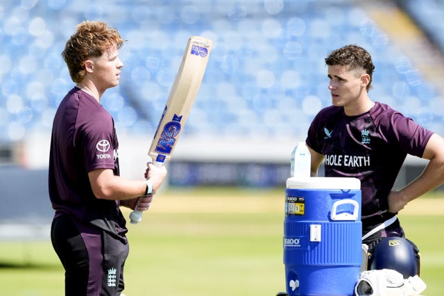 Ollie Pope holds a bat in conversation with Jacob Bethell (right).