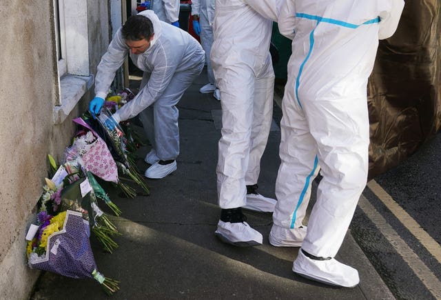 Members of the Garda forensics laying floral tributes next to a house