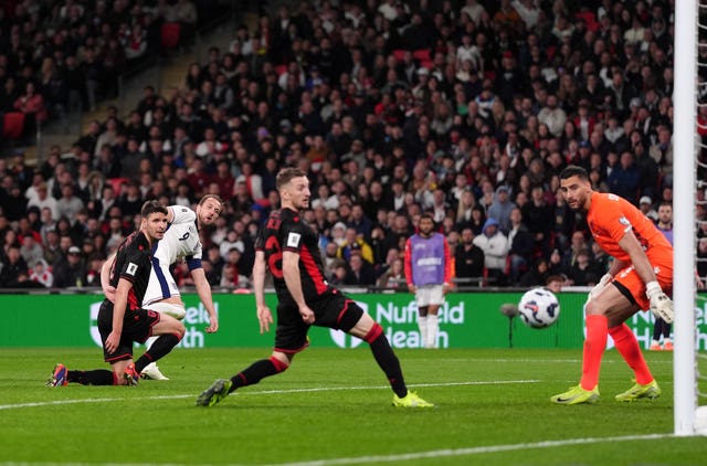 Harry Kane watches hi sshot go into the far corner as Albania's goalkeeper and two defenders watch on