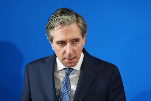 Head and shoulders photo of Simon Harris speaking, in front of a blue wall