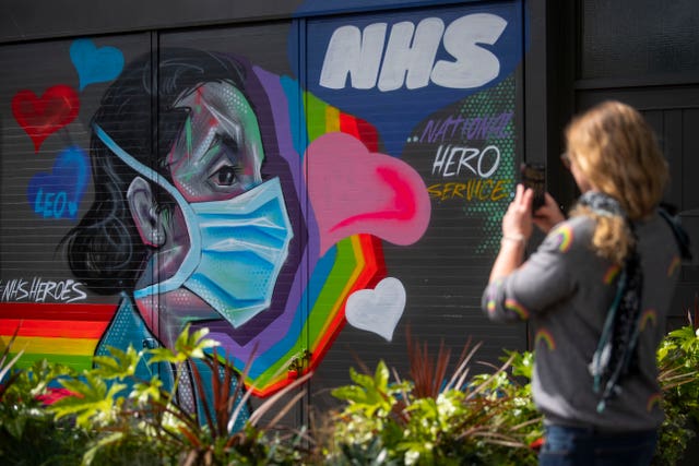 A woman takes a photograph of graffiti in support of the NHS in south-east London
