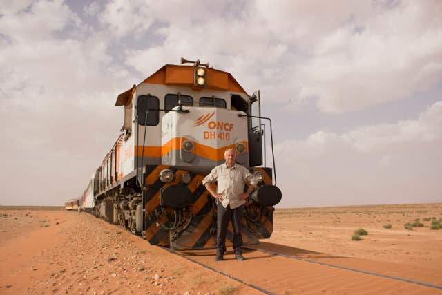 Chris Tarrant stands in front of a train
