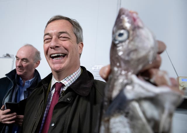 Nigel Farage holds a fish during a stop at the Grimsby Seafood Village