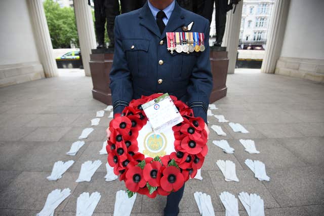 Flight Lieutenant Nigel Painter holds a wreath as he stands among 53 pairs of flying gloves at the Bomber Command Memorial in London’s Green Park which represent the men who died in the Dambusters raids (Kirsty O’Connor/PA)