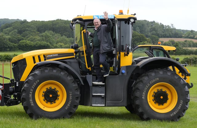 Liberal Democrat leader Sir Ed Davey waves as he climbs out of a JCB Fastrac tractor after driving it during a visit to Owl Lodge in Lacock, Wiltshire, while on the General Election campaign trail