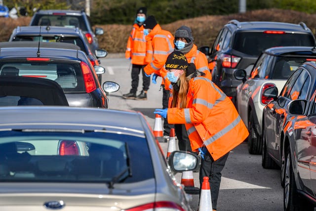 Testing staff hand out kits to motorists attending a surge testing centre