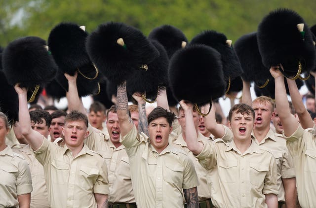 Members of the Welsh Guards remove their headdress as they give three cheers for King Charles III during a full tri-service and Commonwealth rehearsal at RAF Odiham in Hampshire, ahead of their involvement in the second procession that accompanies King Charles III and Queen Camilla from Westminster Abbey back to Buckingham Palace, following the coronation service on May 6 at the abbey in London 