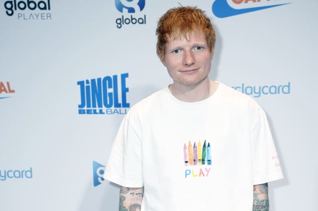 Ed Sheeran with his hands in his pockets wearing a white T-shirt and grey trousers