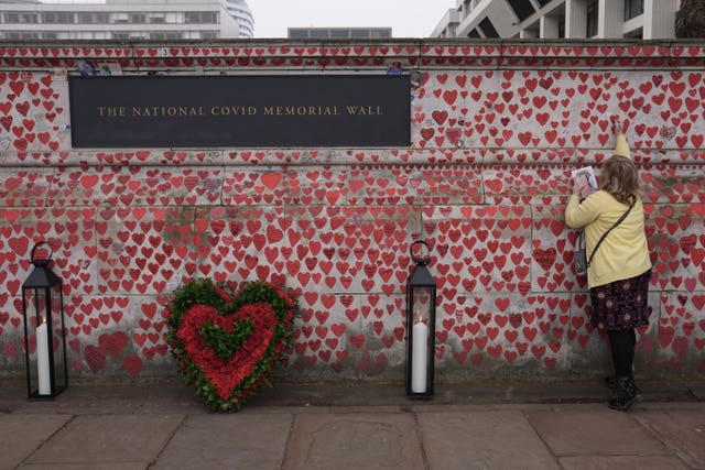 A woman adding a name to the Covid Memorial Wall