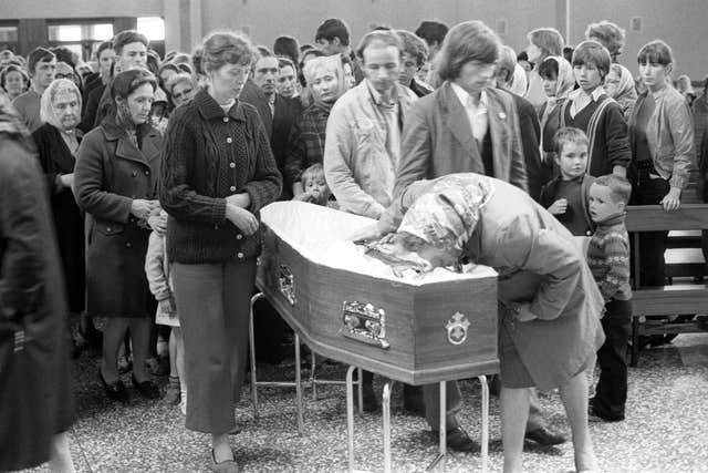 Mourners file past the coffin of Father Hugh Mullan