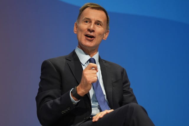 Jeremy Hunt gesturing with a hand while speaking, in front of a blue background