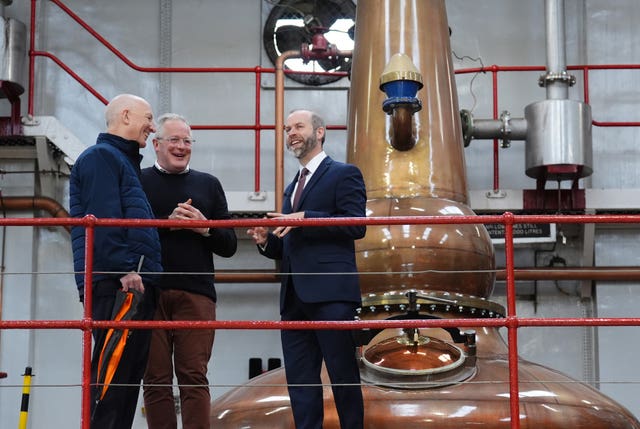 Jonathan Reynolds with two men in front of a whisky still