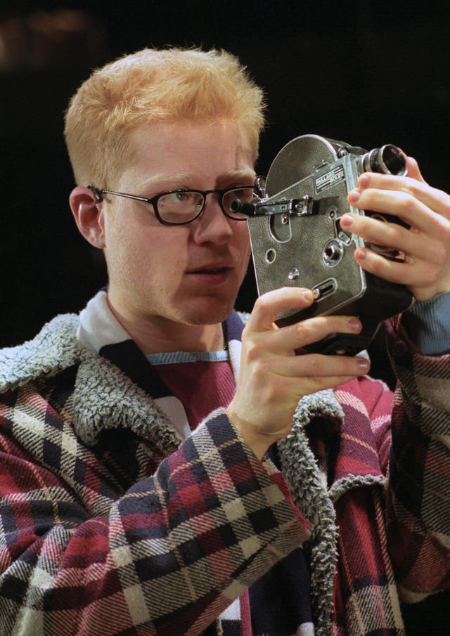 Anthony Rapp on stage peering through a camera
