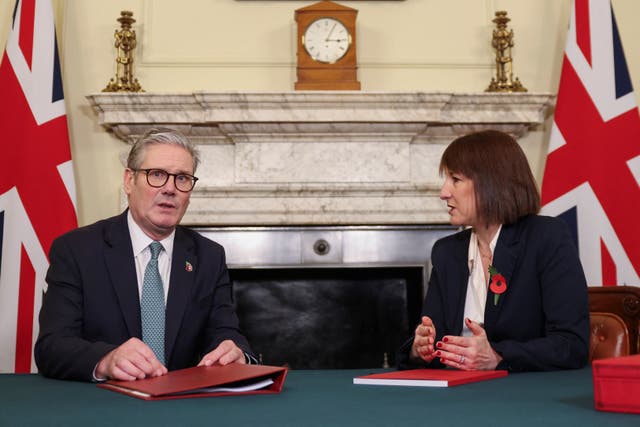 Sir Keir Starmer and Rachel Reeves sitting at a table, with British flags in the background