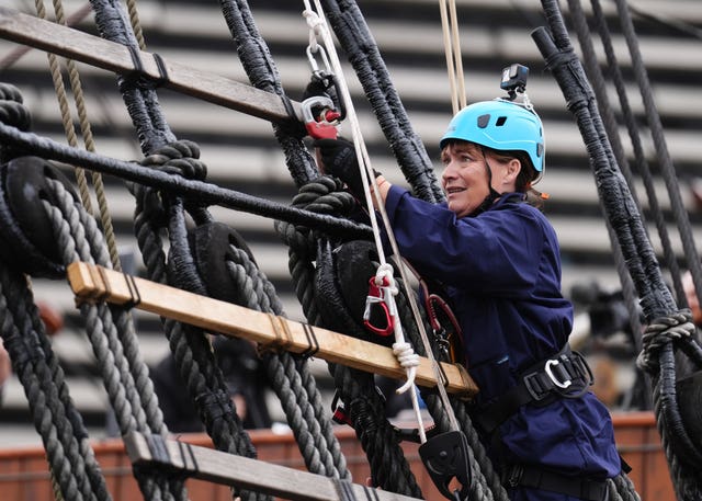 Lorraine Kelly in hard hat and boiler suit climbing the rigging of a ship
