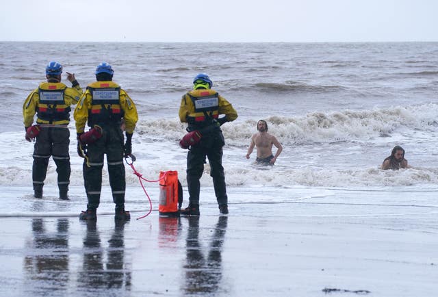 A coastguard search and rescue team ask a group of swimmers to come out of the sea in New Brighton, Merseyside