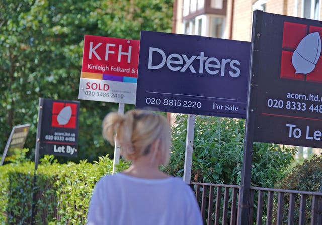 A woman looking at for sale and sold signs