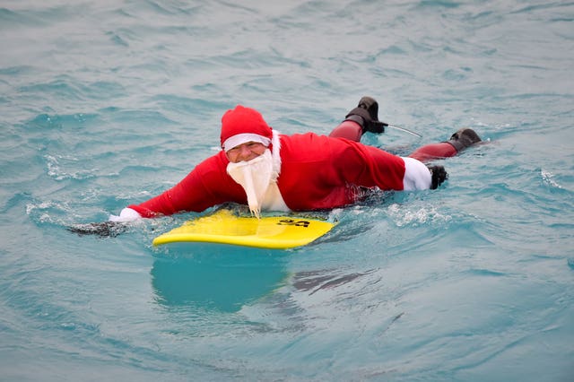 A surfer gets into the festive spirit dressed as Santa as he prepares to enter the waves at the inland surfing lagoon at The Wave, near Bristol