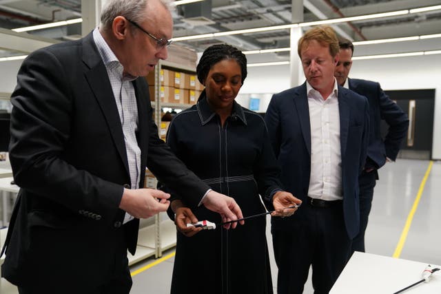 Kemi Badenoch, centre, handles a piece of equipment during a factory tour